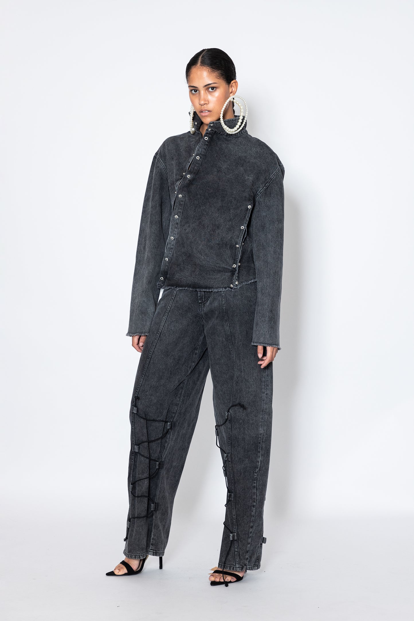 model wears Jade Cropper asymmetric denim jacket with piercings front view gray button closure frayed hem