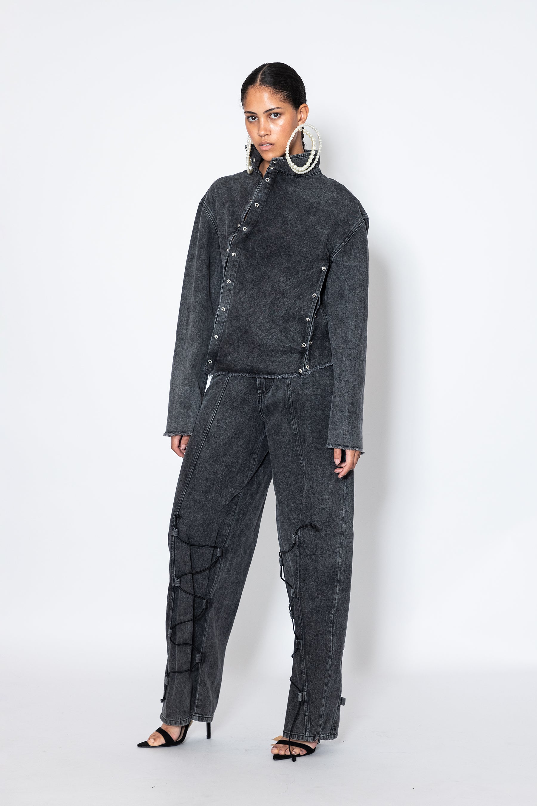 model wears Jade Cropper asymmetric denim jacket with piercings front view gray button closure frayed hem