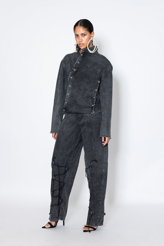 model wears Jade Cropper asymmetric denim jacket with piercings front view gray button closure frayed hem