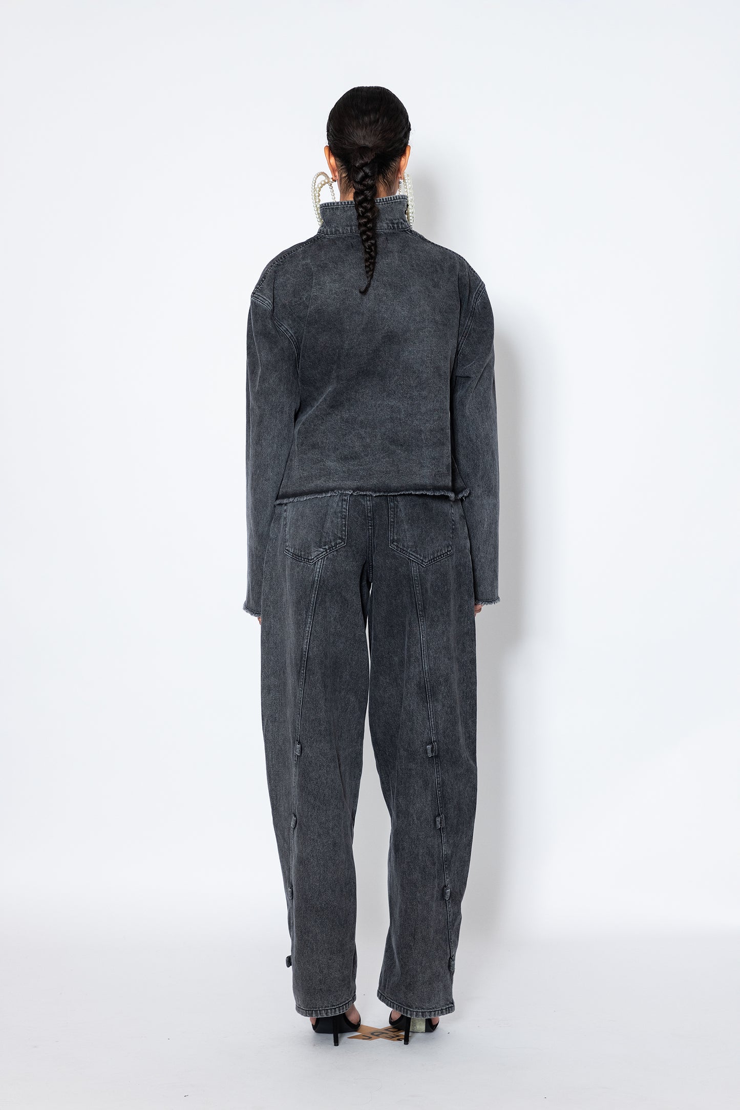 model shows Jade Cropper asymmetric denim jacket with piercings back view gray long sleeves distressed hem