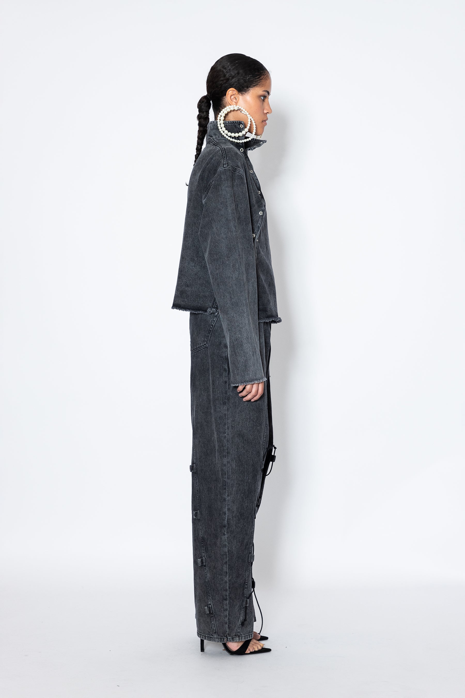 model side angle Jade Cropper asymmetric denim jacket with piercings gray distressed hem button closure sharp cut