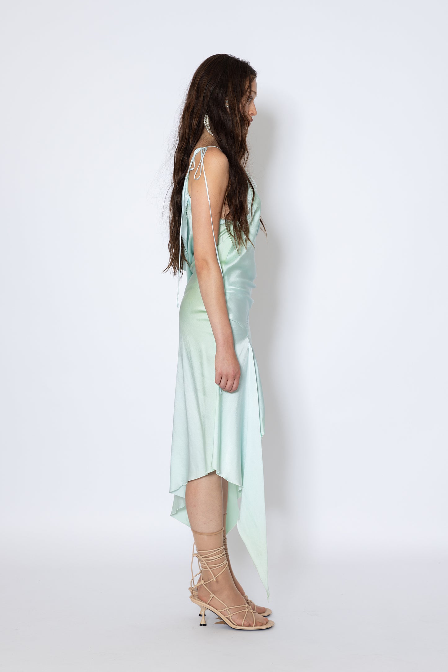 Model wearing Jade Cropper silk fabric asymmetric hem raw edge top with spaghetti straps side view