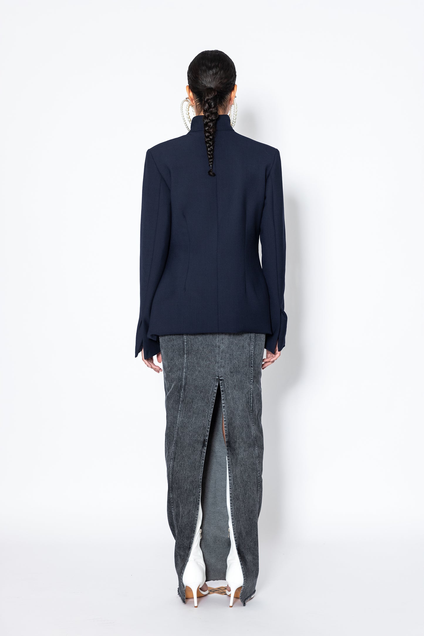 model wearing Jade Cropper navy garment with raw edge tailored cut long sleeves and collar rear view