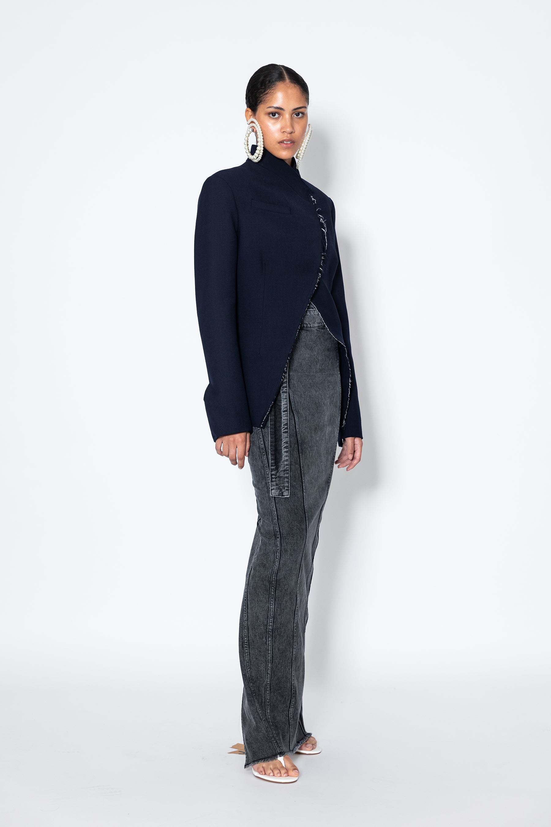 model in Jade Cropper navy garment with structured cut raw edge single button and asymmetrical hem side view