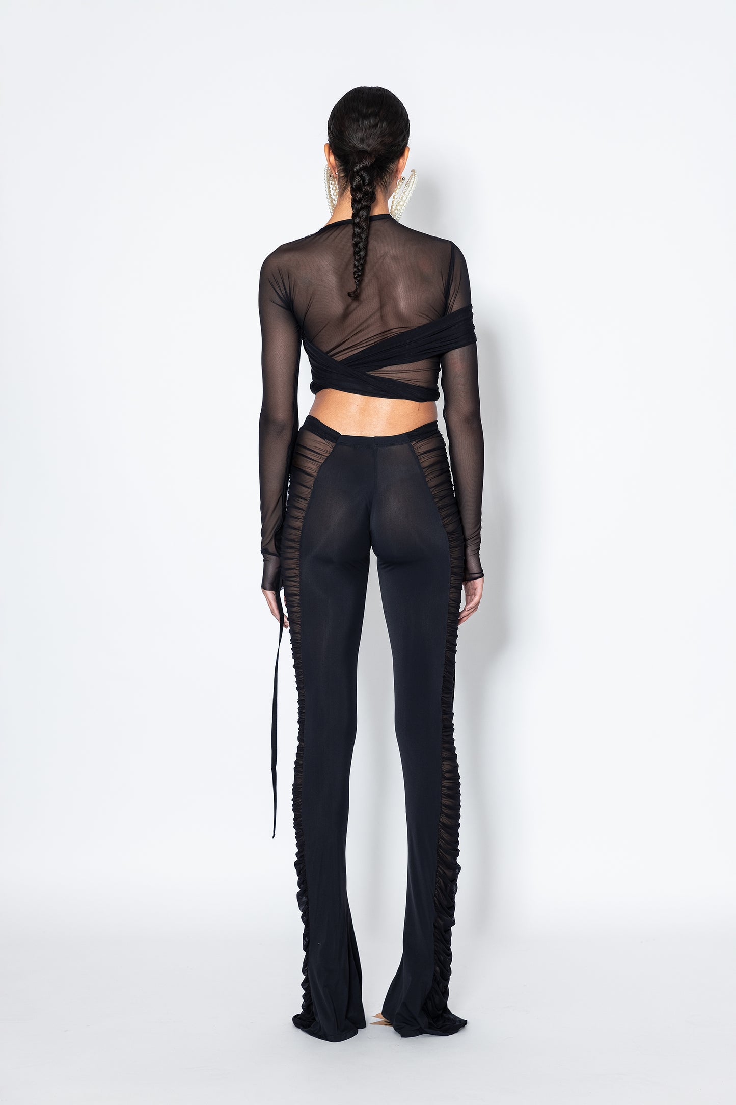 Model back wearing Jade Cropper Black Semi-Sheer Ruched Pants sheer textured mesh fabric long sleeves wrap design