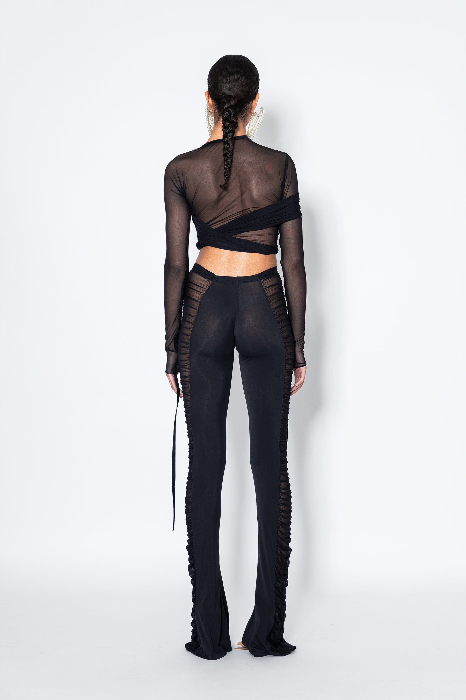 Model back wearing Jade Cropper Black Semi-Sheer Ruched Pants sheer textured mesh fabric long sleeves wrap design