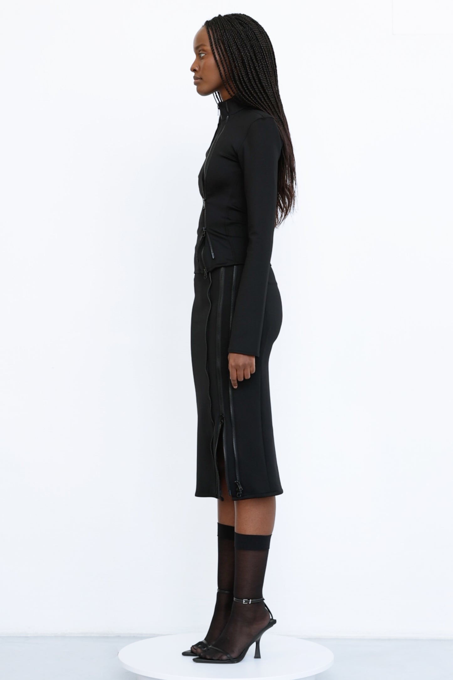 Jade Cropper Double Zipper Midi Skirt fitted cut on model side view with zip closure and long sleeves in black