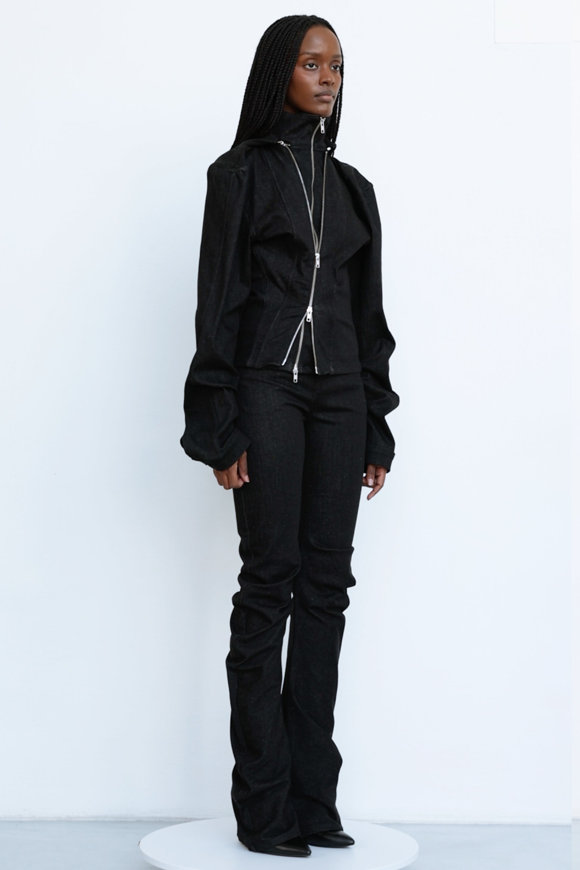 Jade Cropper black fitted garment with high collar puffed sleeves and zipper side profile