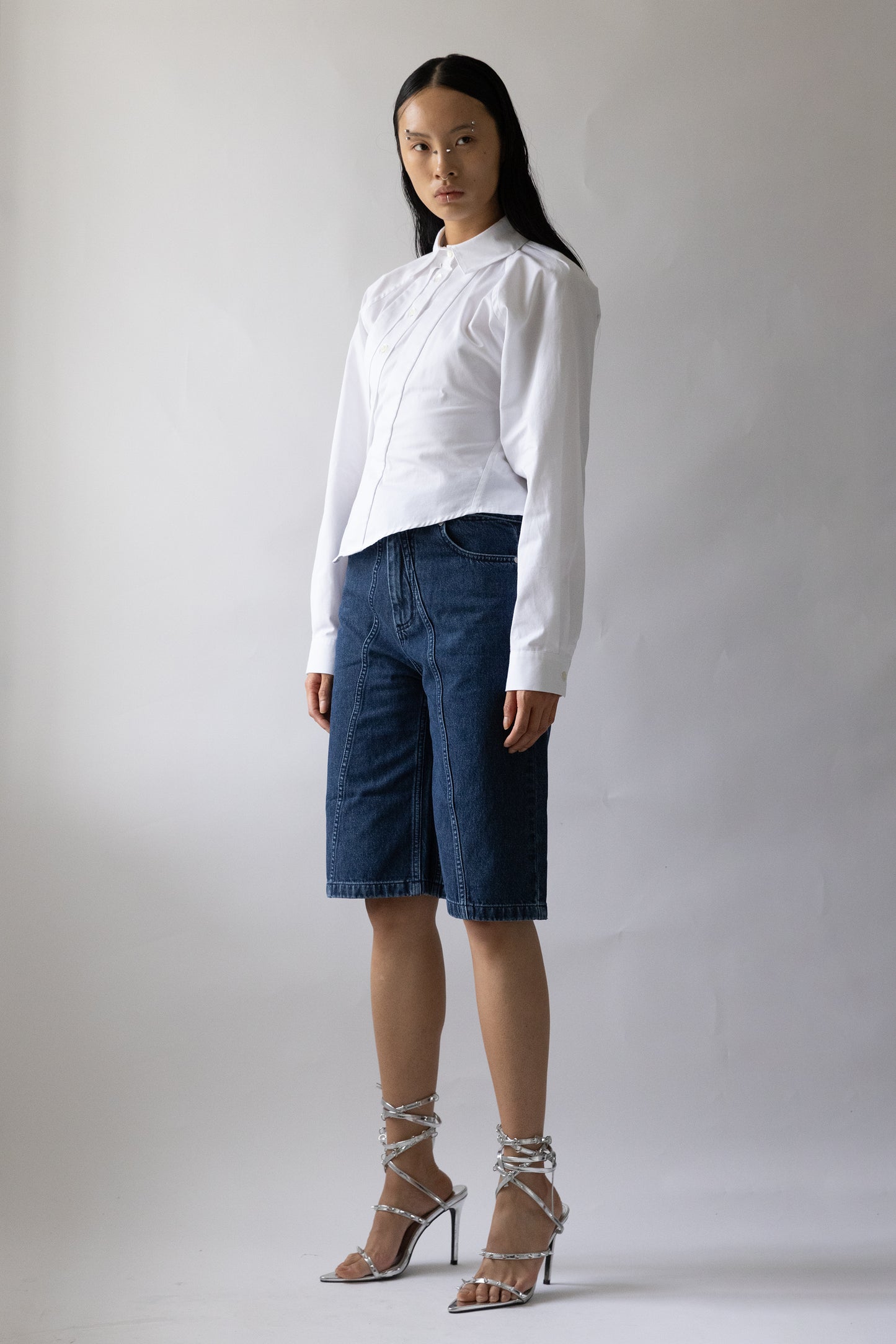 model front view shows high-waisted blue denim garment featuring front seam and two pockets by Jade Cropper