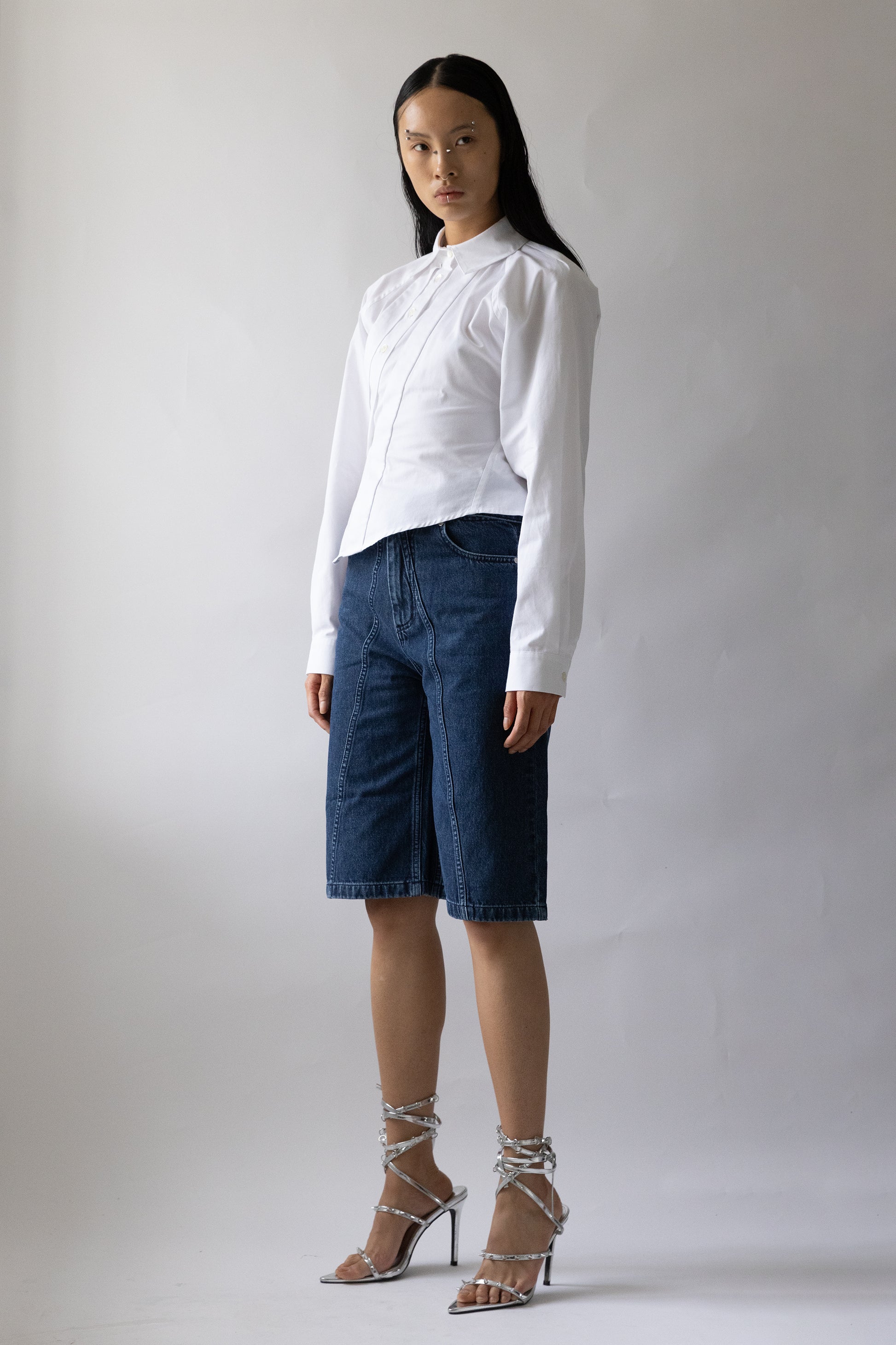 model front view shows high-waisted blue denim garment featuring front seam and two pockets by Jade Cropper