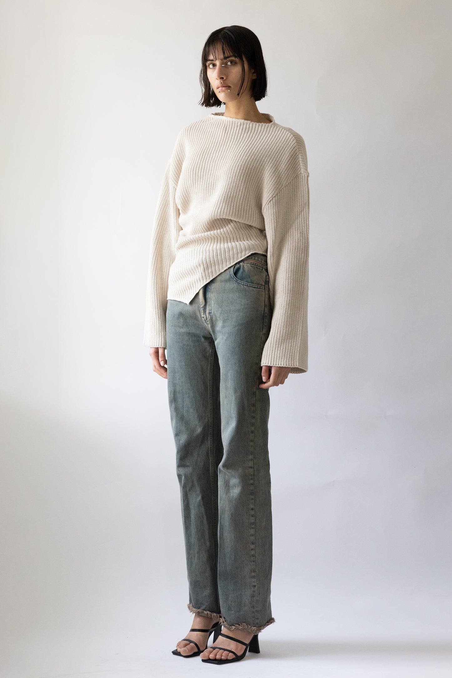 Jade Cropper side view of ribbed beige garment with wide sleeves cropped cut and asymmetric hem