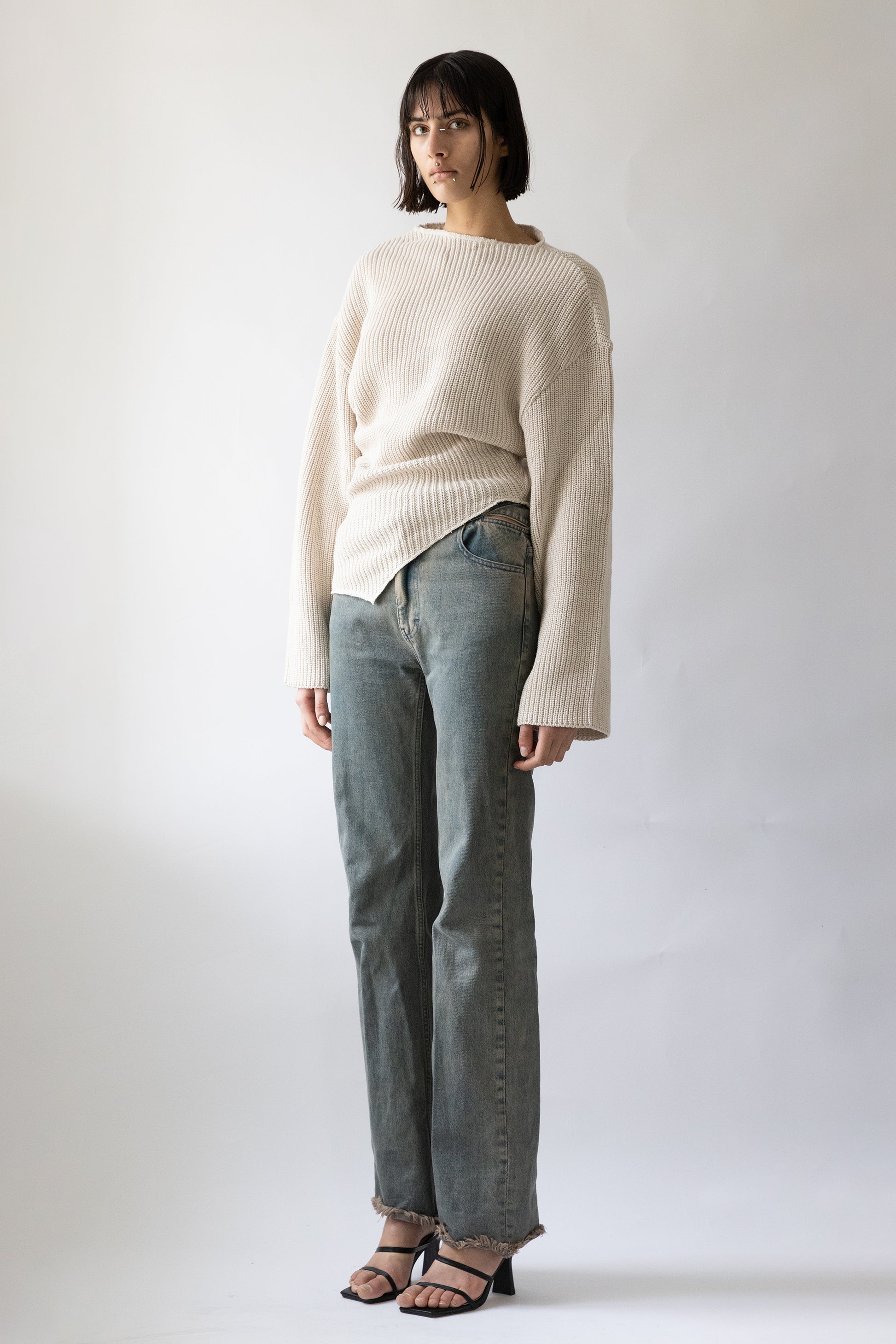 Jade Cropper side view of ribbed beige garment with wide sleeves cropped cut and asymmetric hem