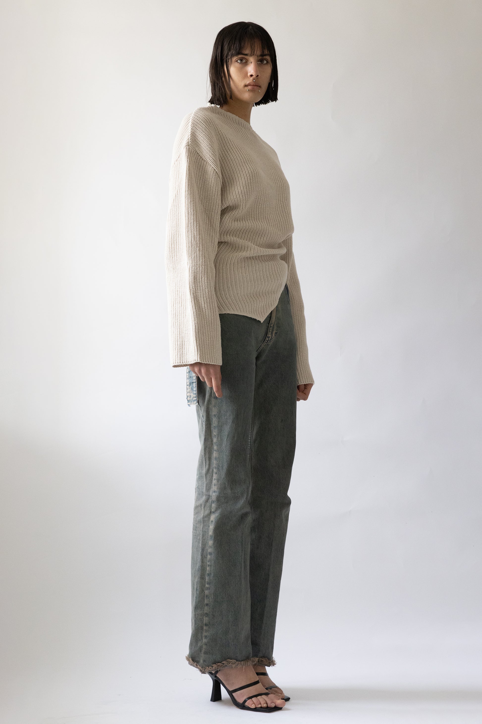 Jade Cropper side view of ribbed beige garment with long sleeves high neck and side slit