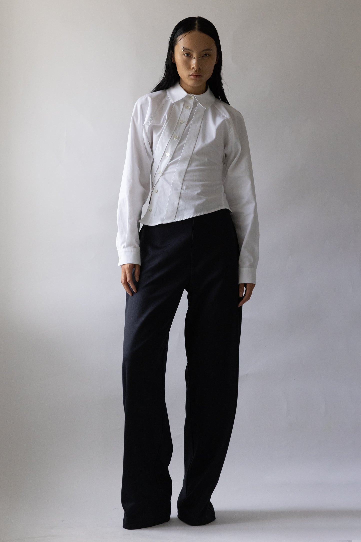 Model wears Jade Cropper Asymmetric Shirt White with fitted silhouette button front long sleeves and collared neckline front view