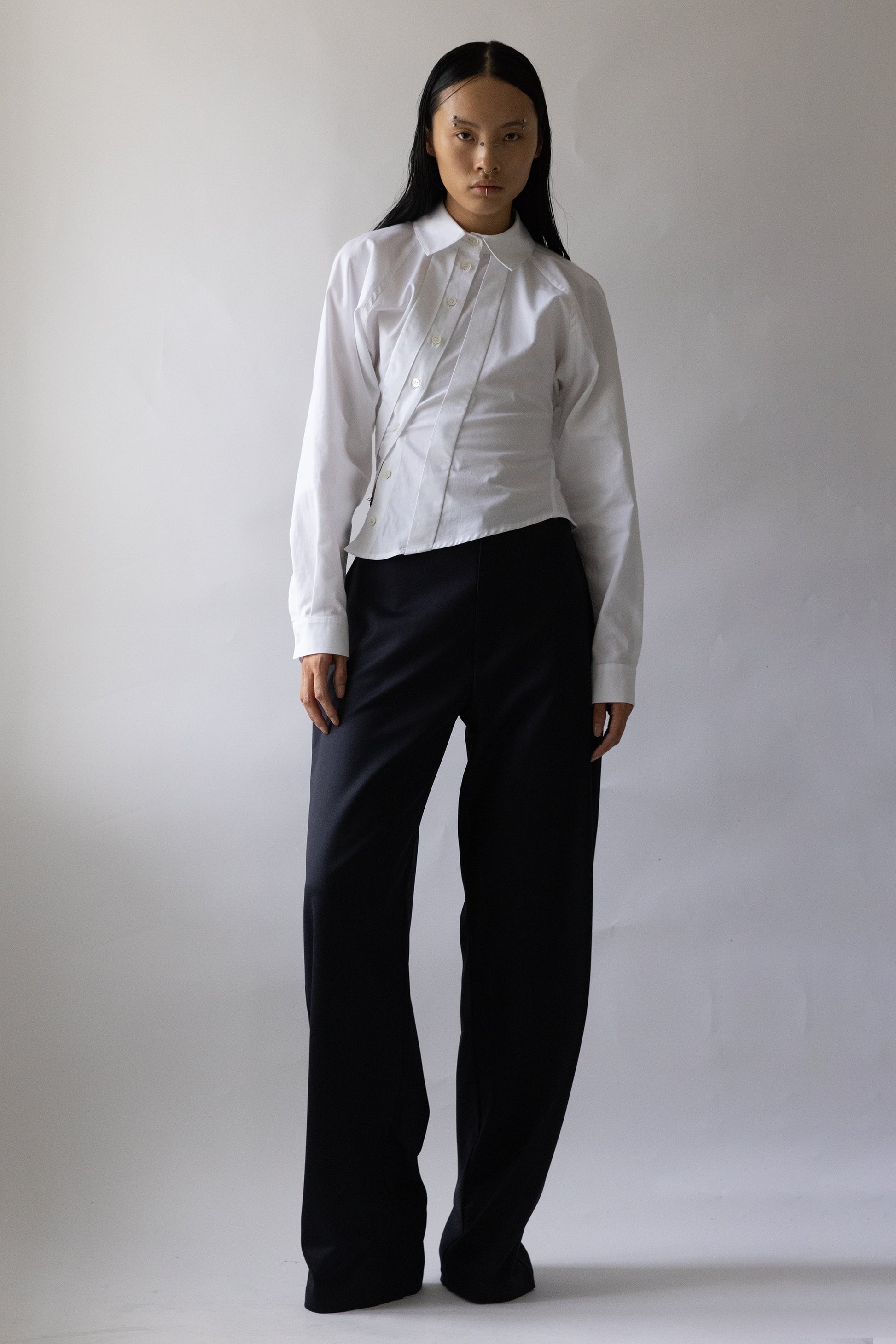 Model wears Jade Cropper Asymmetric Shirt White with fitted silhouette button front long sleeves and collared neckline front view