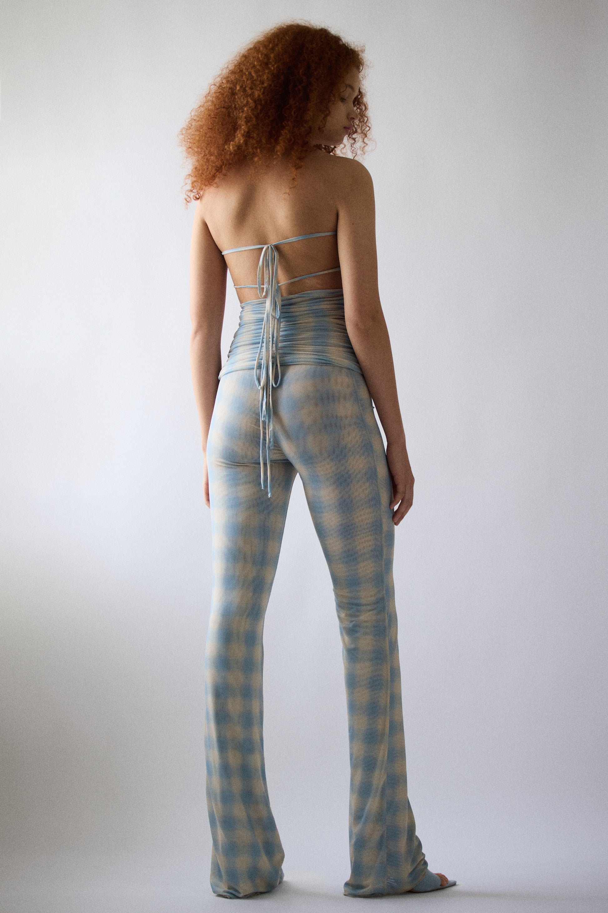 Model wearing Jade Cropper high waist back view with ruched detail, tie closure and flared legs