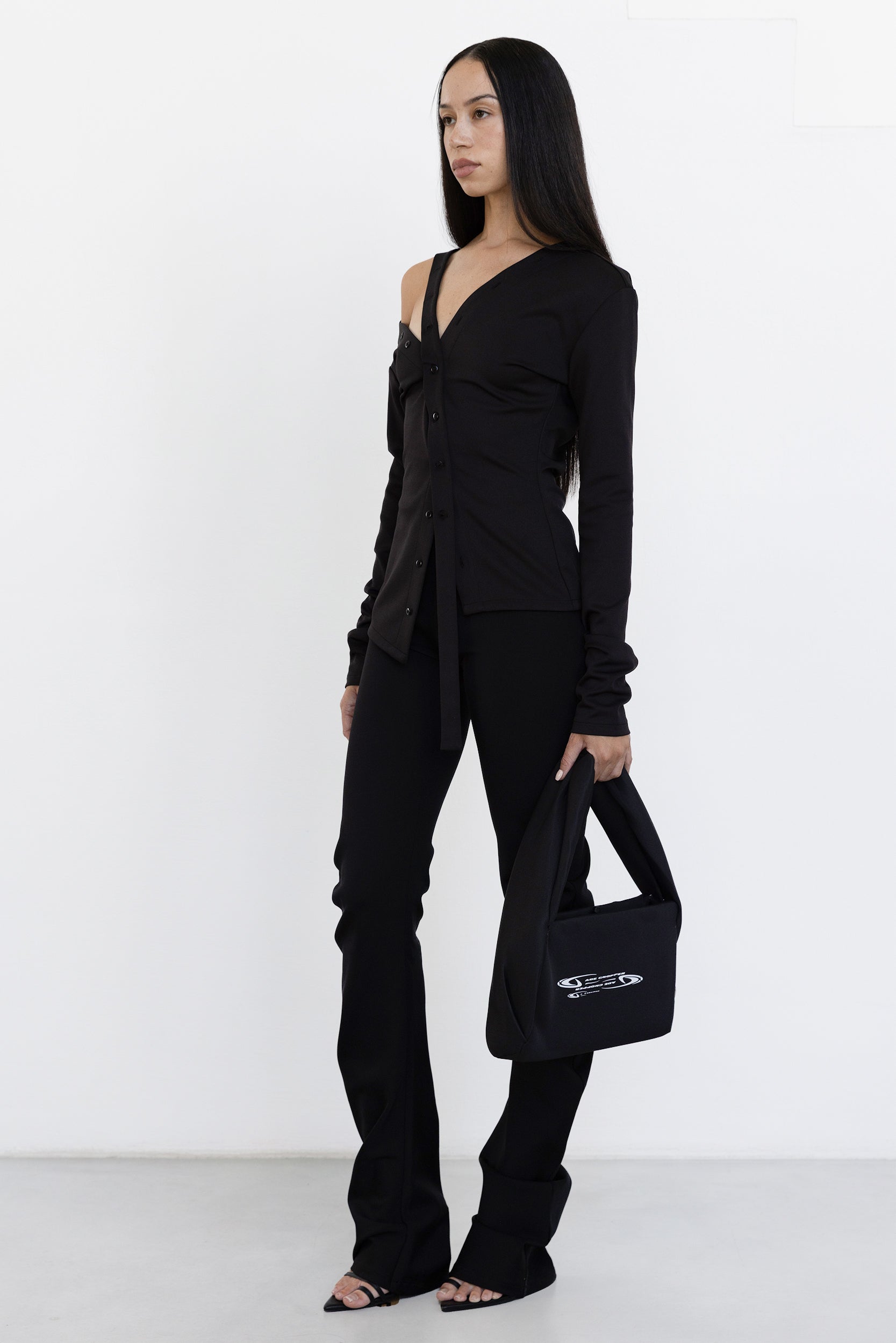 Jade Cropper Asymmetric Off Shoulder Top in black side view shows off-shoulder fit, button front, long sleeve, and tie detail