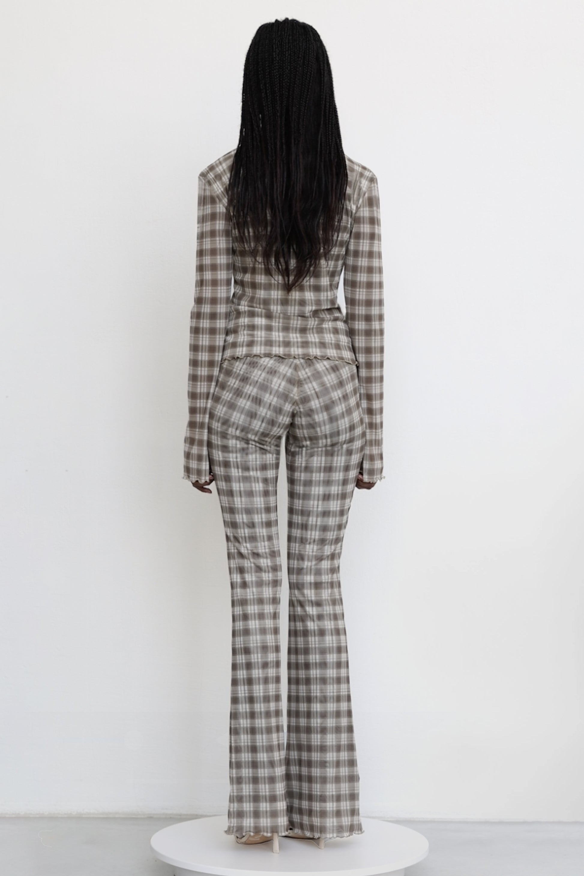 Model wears Jade Cropper garment in gray plaid pattern fitted back flared hem long sleeves rear view