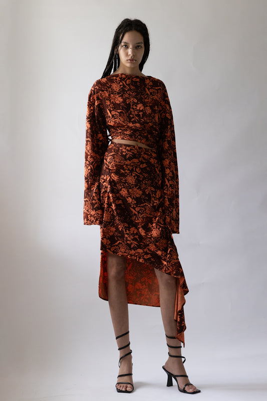 Model wears orange Draped Asymmetric Wrap Skirt by Jade Cropper with long sleeves floral pattern asymmetrical hem cropped length front view