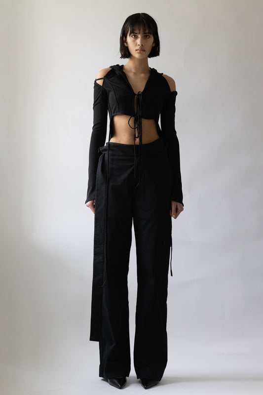 Black cropped hooded cardigan with cut-out shoulders and front tie detail on model by Jade Cropper