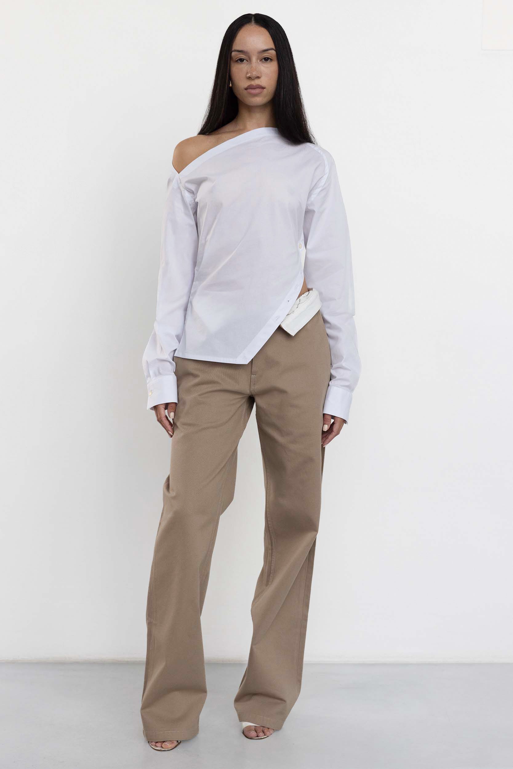 Jade Cropper white garment with open shoulders long sleeves button closure and asymmetrical hem front view