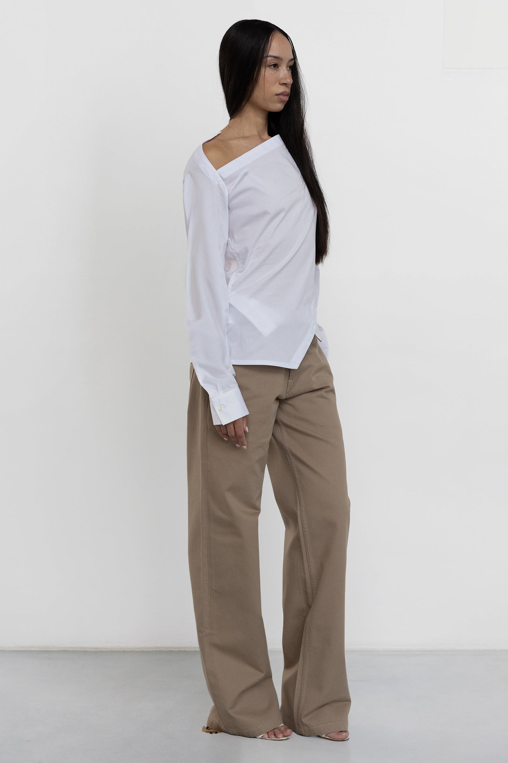 Jade Cropper white garment with asymmetrical cut long sleeves button cuffs and slight sheen side view